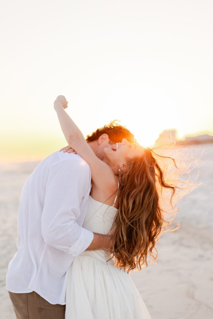 Joyful couple sharing an intimate sunset moment on the beach during their Gulf Shores Alabama engagement session.
