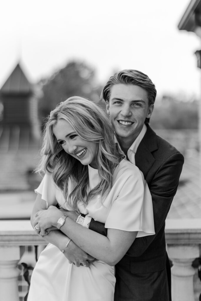 Couple laughing together during their engagement session at Fountainview Mansion in Auburn, Alabama, with elegant architecture in the background. 