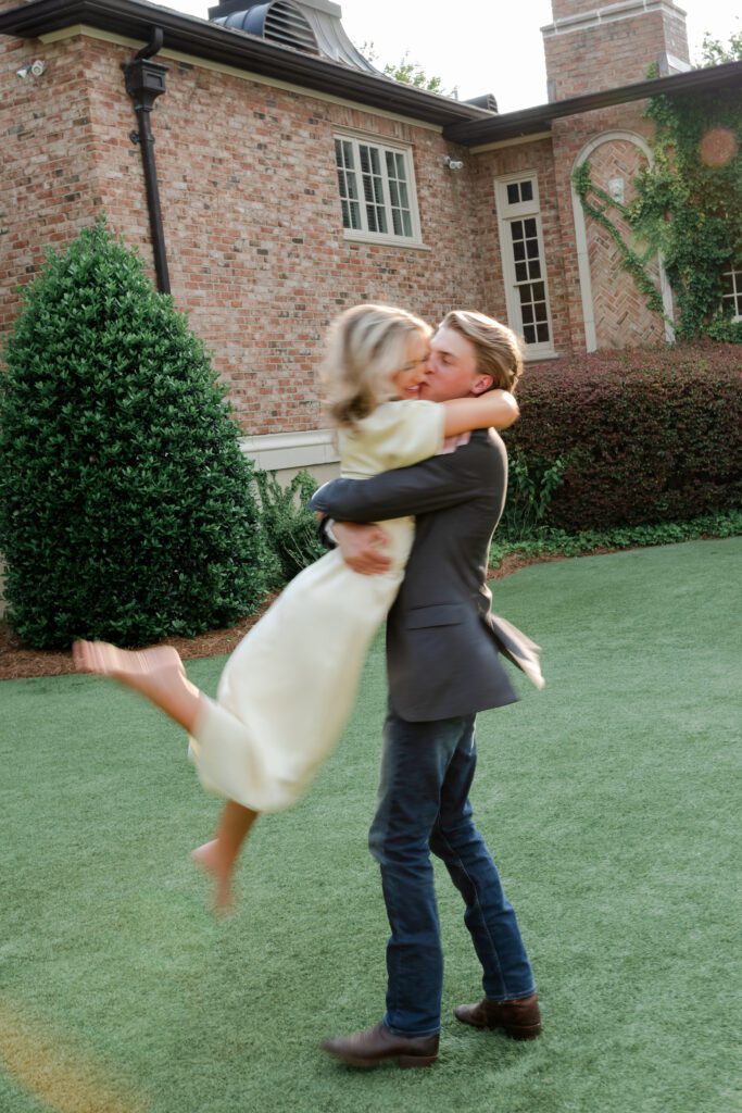 Playful engagement portrait of a couple twirling together outside Fountainview Mansion in Auburn, Alabama