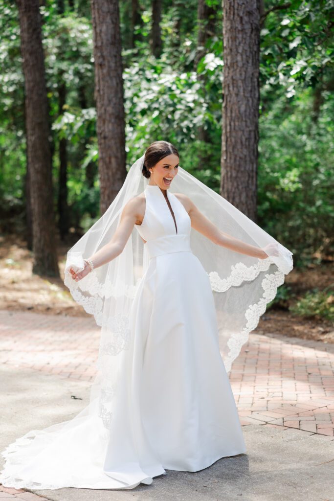 Grace holds her lace-trimmed veil during an outdoor bridal portrait at Steelwood Country Club