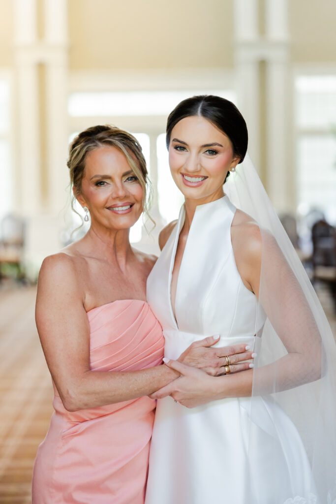 Grace poses with her mother in a coral dress before her Steelwood Country Club wedding