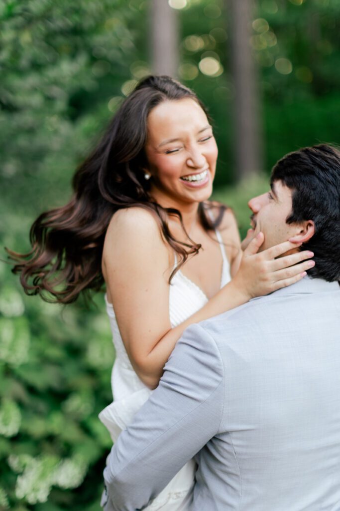 Emily laughs while holding Brody’s face during their Birmingham Botanical Gardens engagement session.