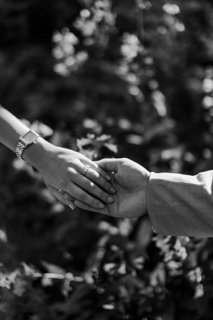 Black-and-white close-up of Emily’s engagement ring as she holds Brody’s hand.