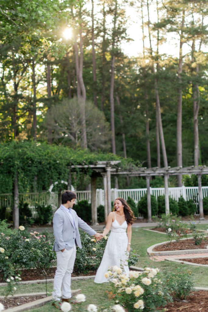 Emily and Brody hold hands and laugh together in the rose garden at Birmingham Botanical Gardens.